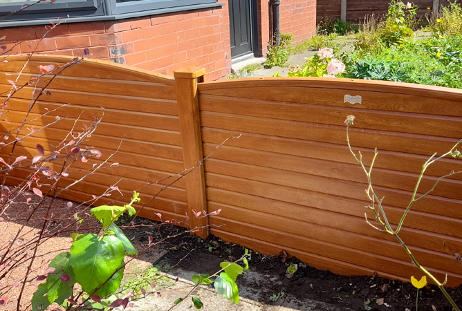 Golden oak woodgrain wrapped fencing with a bowed top