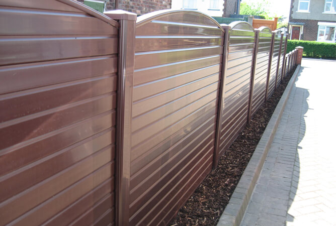 High level and low level gloss brown UPVC fencing with a bow top