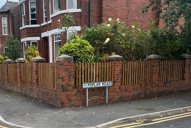 Picket fence panels between brick pillars