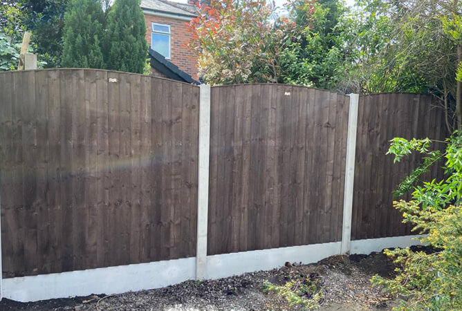 Brown vertical lap fence panels with bowed tops
