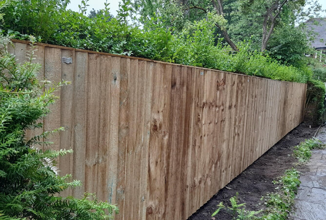 Pressure treated vertical lap fence panels attached to timber posts